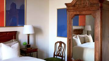 Una camera d'albergo con un letto grande, un armadio in legno, un comodino con una lampada e uno specchio.