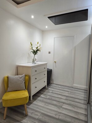 A room with a white dresser, a yellow chair, and a door. - Pedro's Place Battersea (London)