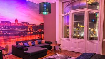 A room with a large window, a sofa, a small table, and a chair.