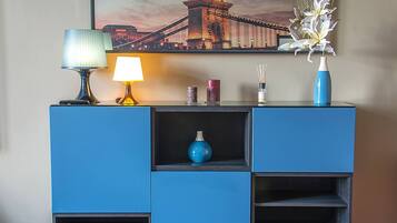 A blue cabinet with a lamp, a vase, and a framed picture of a bridge.
