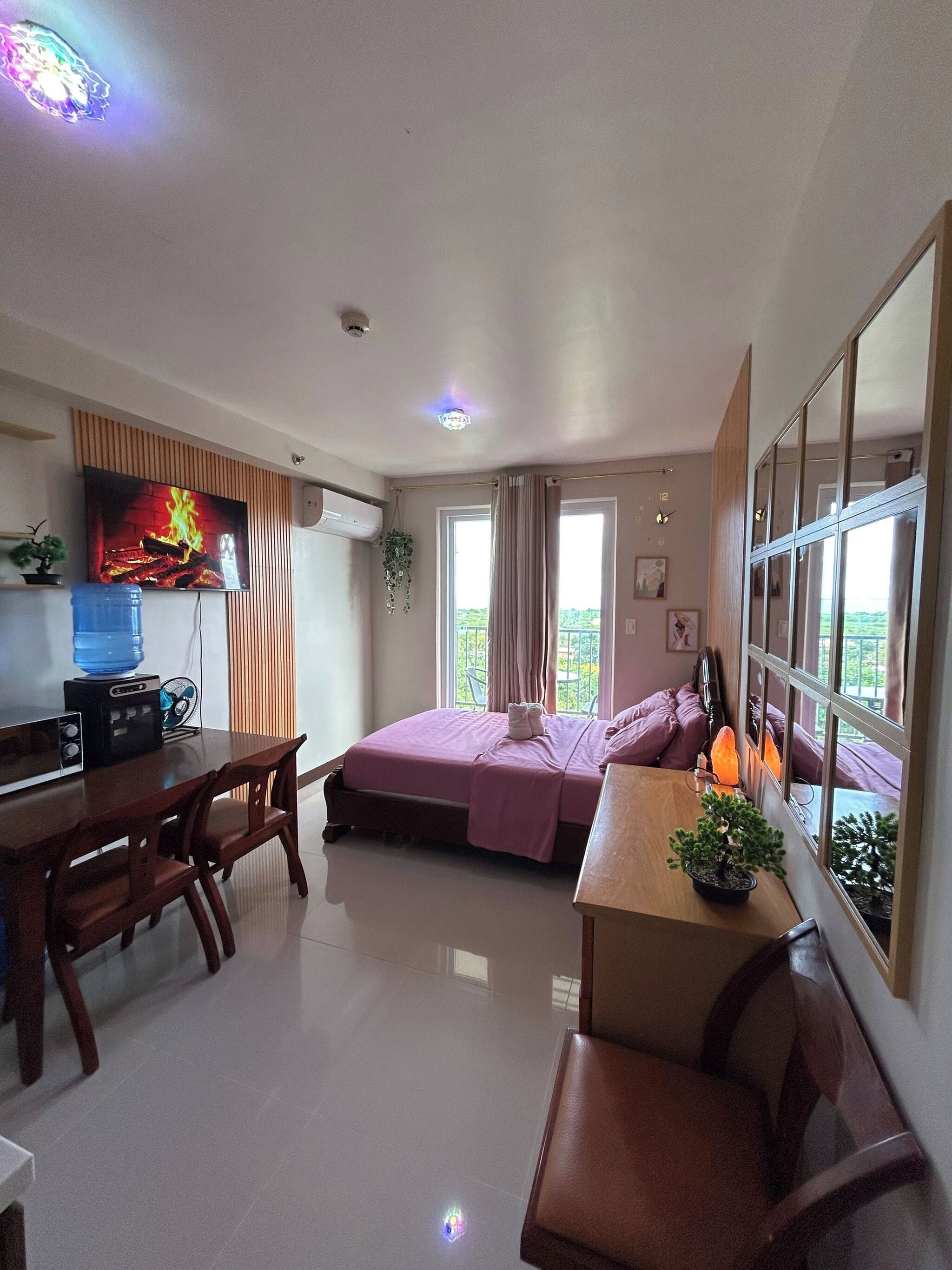 Una habitación con cama, escritorio, silla, dispensador de agua y televisor.