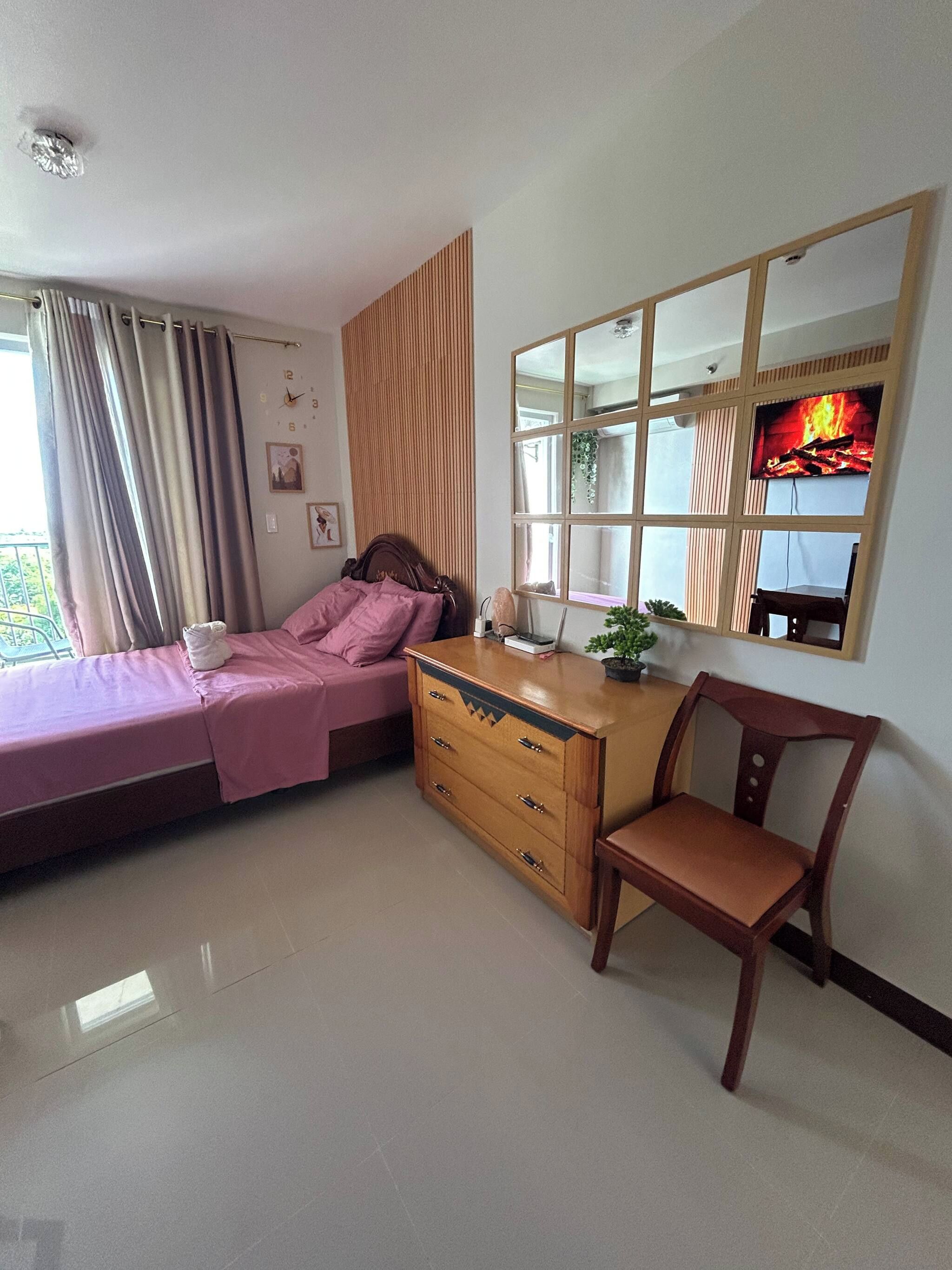 Un dormitorio con cama, cómoda, silla y un espejo grande.