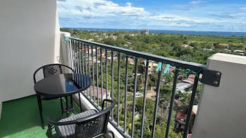 A balcony with a table and chairs, a view of a coastal area, and an LG dual inverter air conditioning unit.