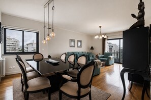Ein modernes Wohnzimmer mit Essbereich, großen Fenstern und Blick auf die Stadt.