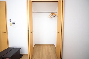 A walk-in closet with a wooden floor, a hanging rod, and a bench. - goom Monthly Nakasu Maxim (Fukuoka City Chuo-ku Haruyoshi)
