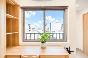 A room with a window, a potted plant, a wooden table, and a chair. - Minh Khang Apartment (Ngu Hanh Son)
