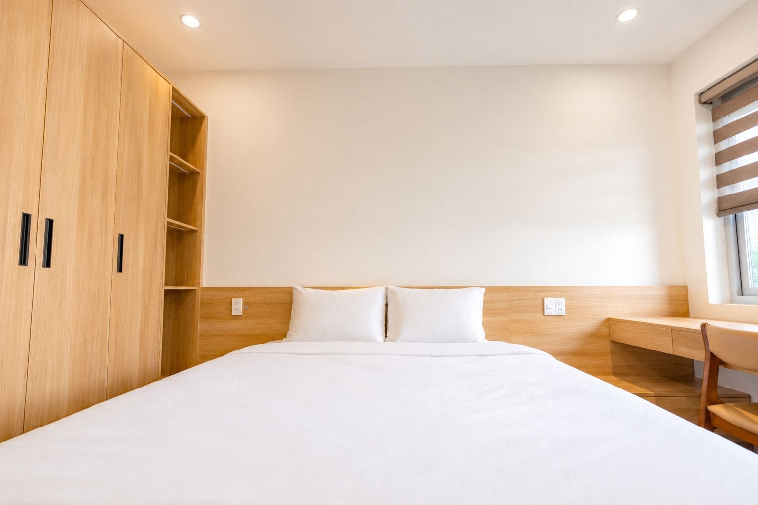 Ein Hotelzimmer mit einem großen Bett, einem Holzschrank und einem Schreibtisch mit Stuhl.