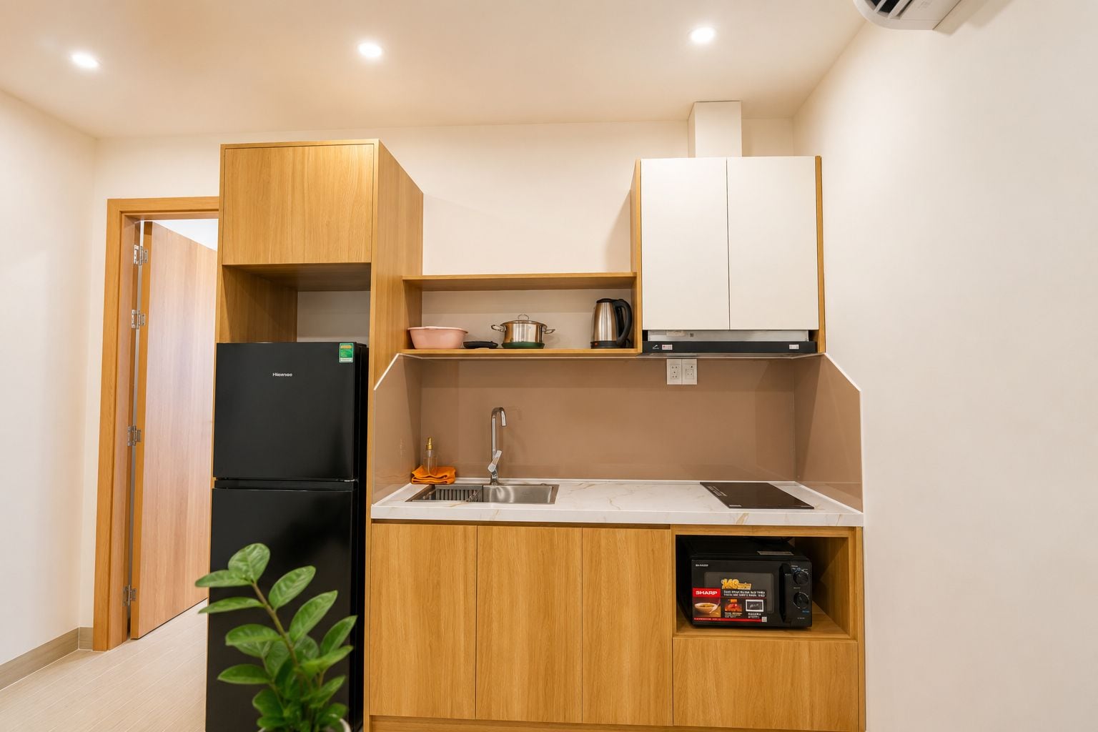 A compact kitchen with a refrigerator, sink, and a microwave.