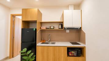 A compact kitchen with a refrigerator, sink, and a microwave.