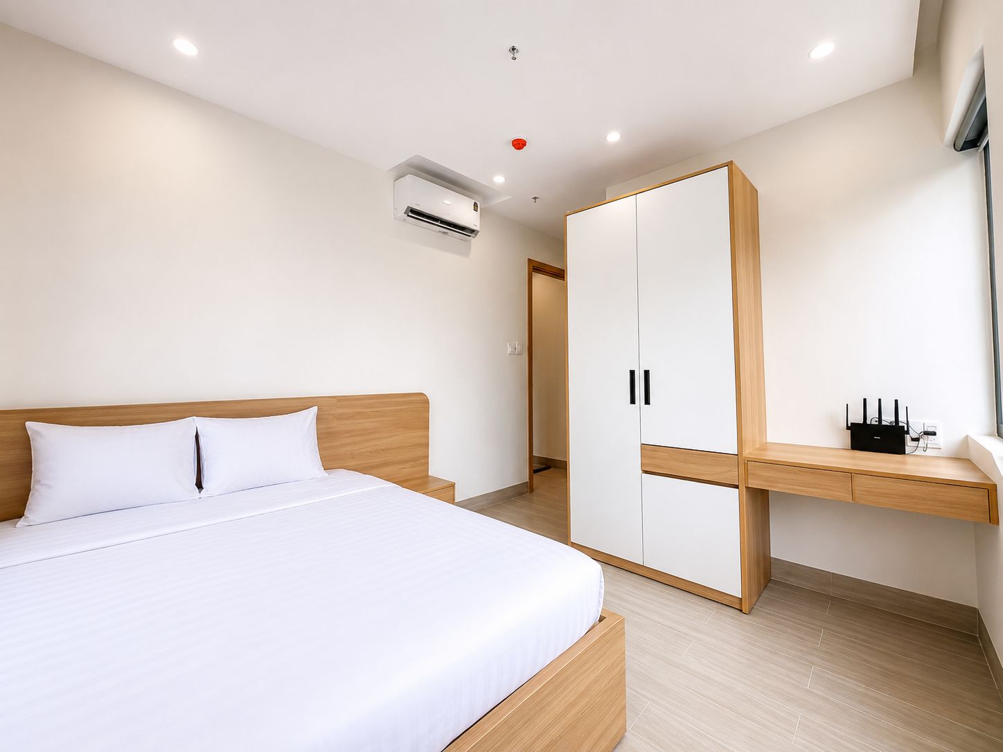 Una habitación de hotel moderna con cama, armario, mesita de noche y aire acondicionado.
