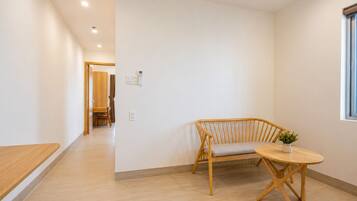 Een modern interieur met een houten bank, een ronde tafel en een rieten zithoek.