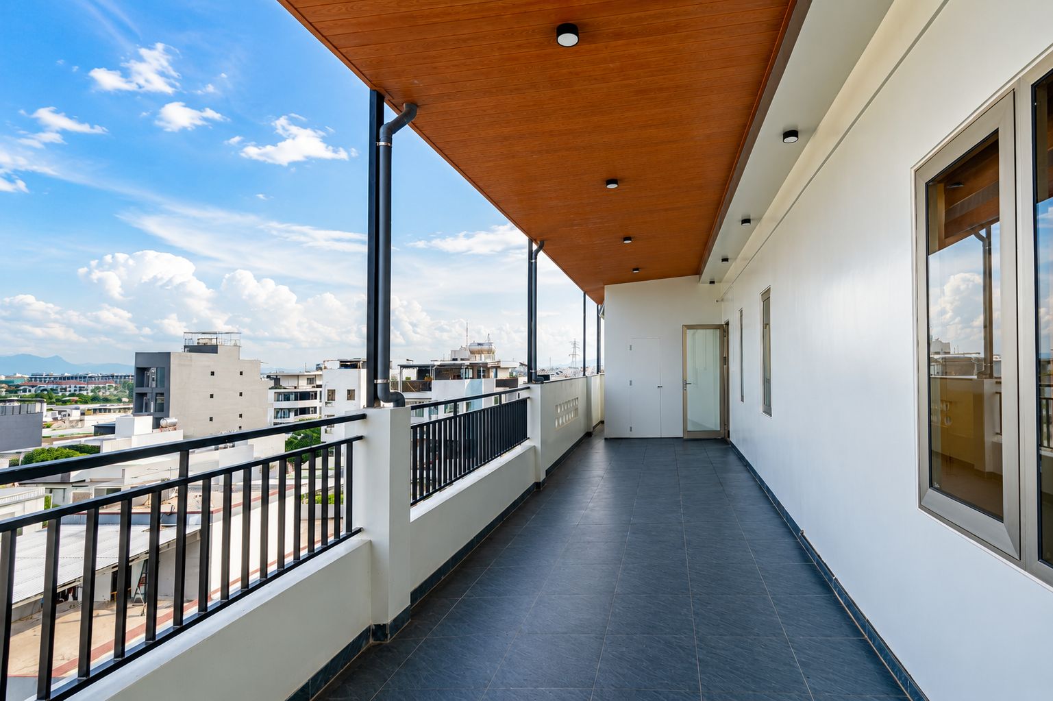 Un balcón con vistas a la ciudad, techo de madera y una puerta que da a un espacio interior.