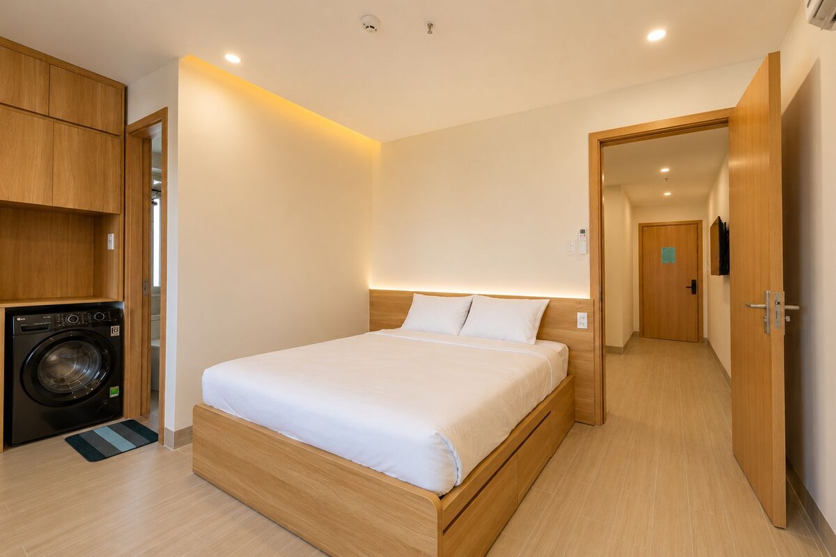 A hotel room with a bed, a washing machine, and a wooden wardrobe.