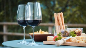 Ein Tisch mit zwei Weingläsern, einem Käsebrett und Grissini.