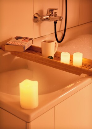 Una banyera amb un llibre, una tassa i espelmes.