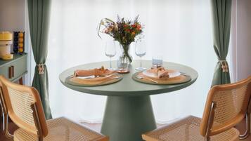 Ein runder Tisch mit zwei Stühlen, einer Vase mit Blumen und zwei Weingläsern.