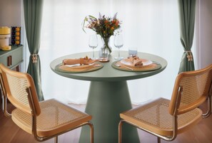 A round table with two chairs, a vase with flowers, and two wine glasses.