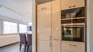 Une cuisine moderne dotée d’un four encastré et d’un coin repas avec des chaises.