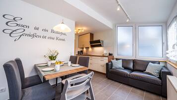 Ein modernes Wohnzimmer mit Essbereich, einer Couch und einer Küche im Hintergrund.