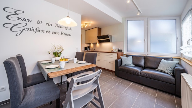 Un salon moderne avec un coin repas, un canapé et une cuisine en arrière-plan.