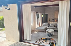 A modern interior with a sofa set, a round table, and a view of the outside. - Idyllic Bungalow with Lake View & Pool in Tignale (Aer)