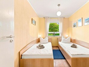 Ein Hotelzimmer mit zwei Betten, einem Fenster mit Blick auf Grünflächen und einer Deckenleuchte.