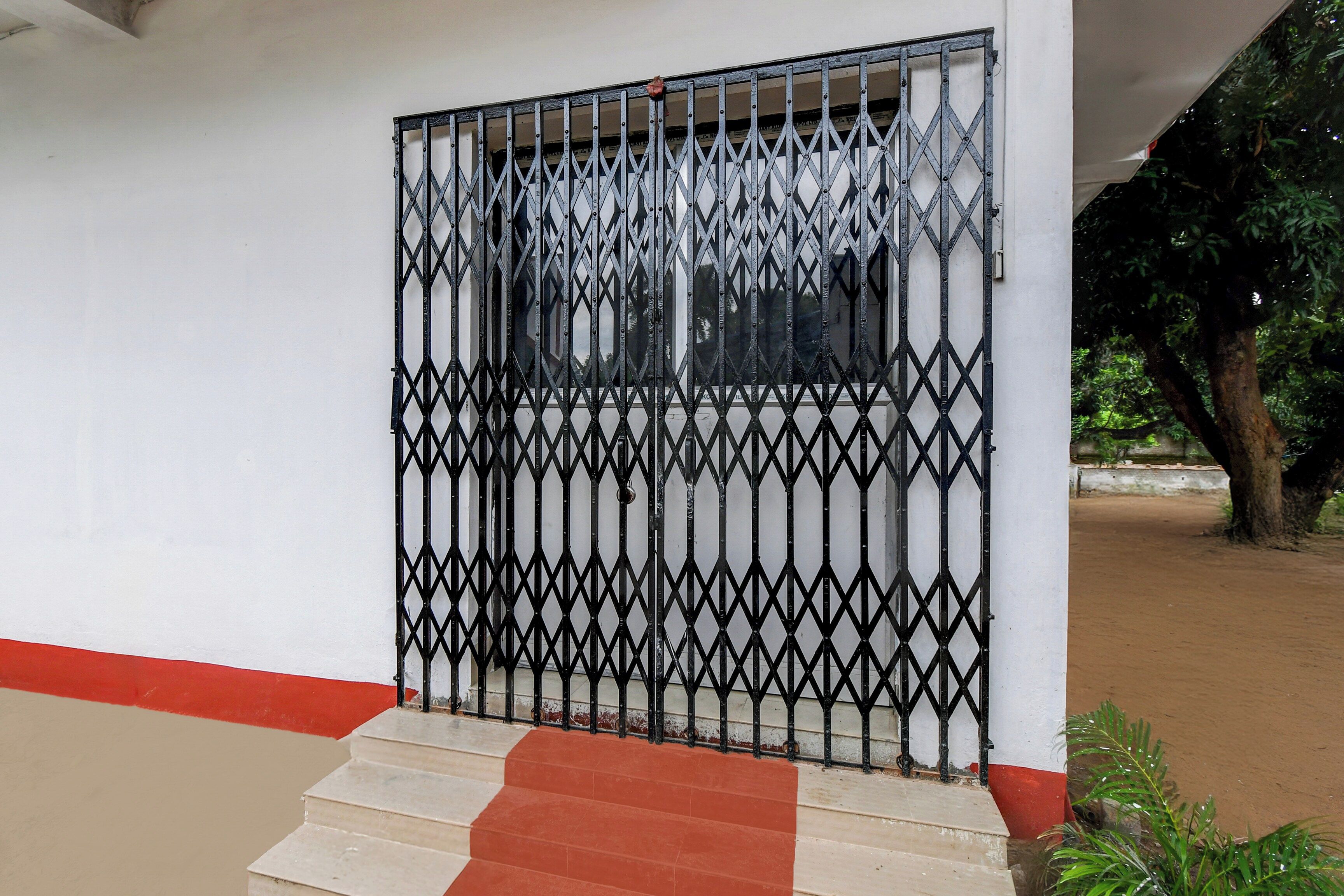 Uma entrada murada com portão de metal e degraus que levam a um edifício.