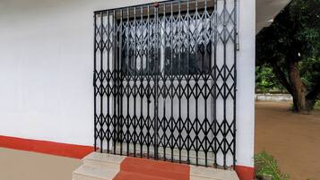 Uma entrada murada com portão de metal e degraus que levam a um edifício.