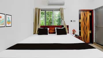 A hotel room with a bed, a window with curtains, an air conditioning unit, and a door with a unique design.