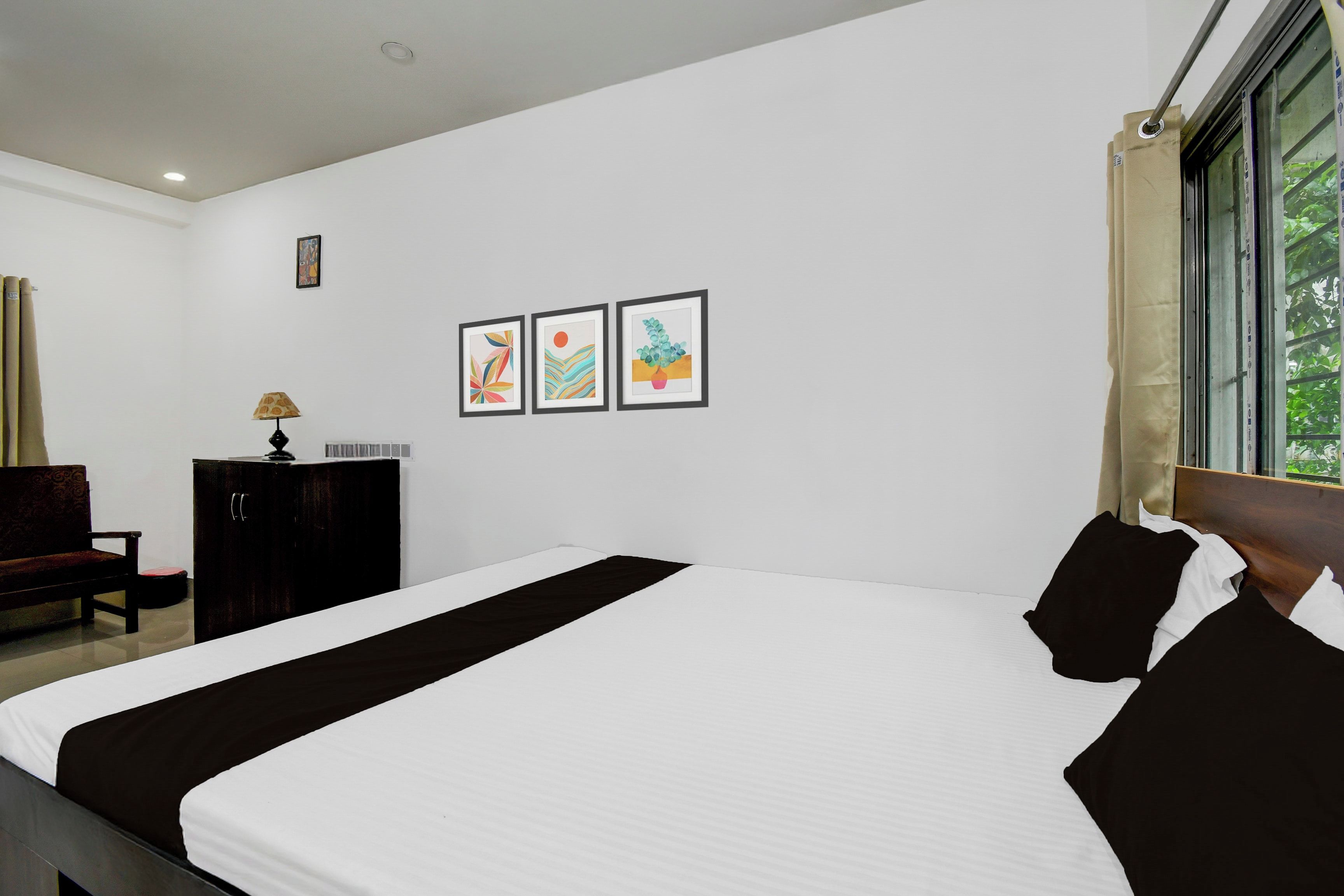 Habitación de hotel con una cama grande, un escritorio, una silla y tres cuadros en la pared.