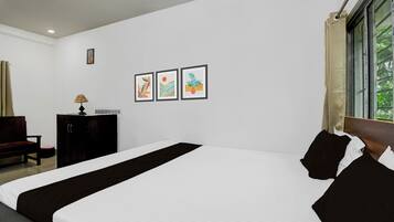 Habitación de hotel con una cama grande, un escritorio, una silla y tres cuadros en la pared.