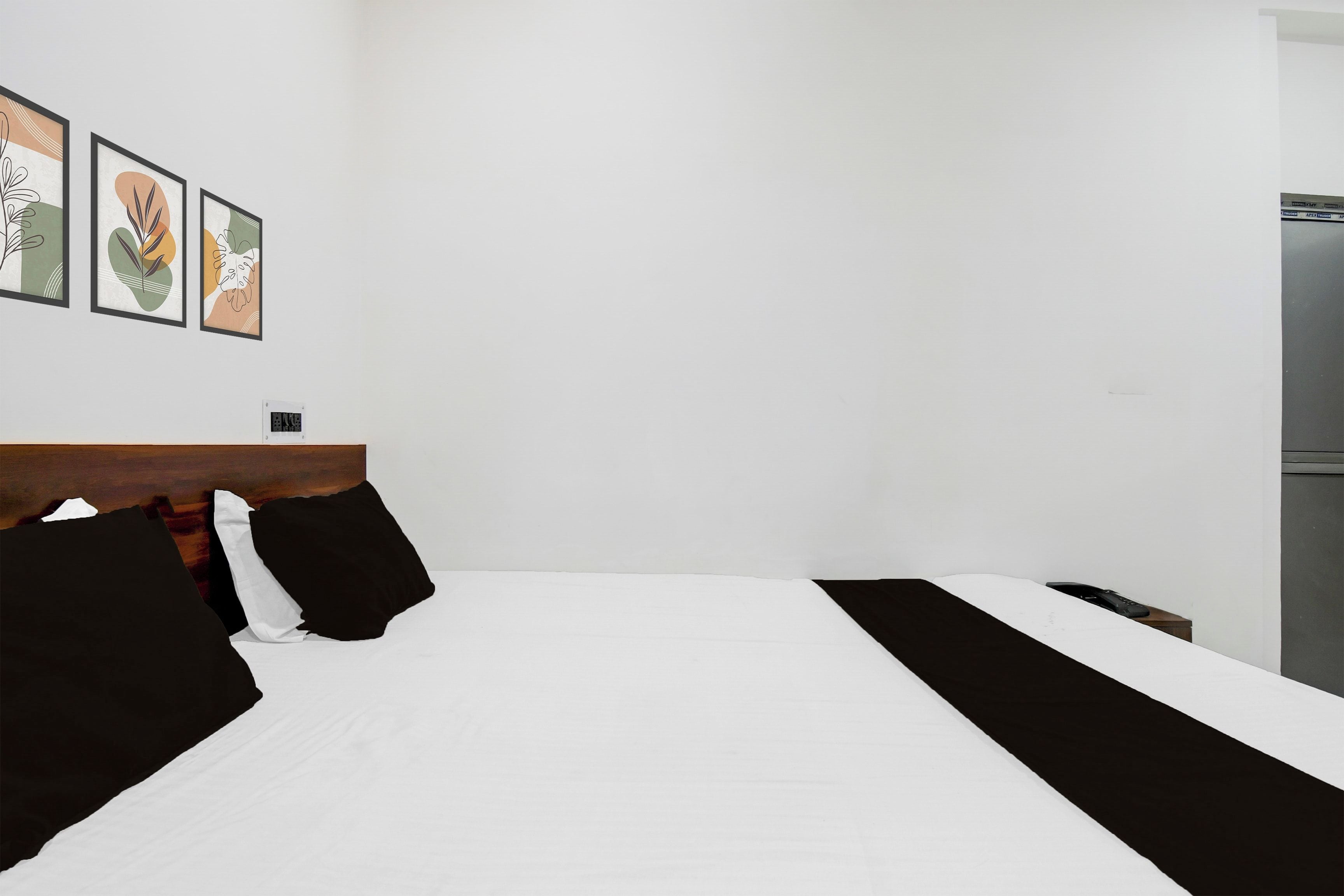 Habitación de hotel con cama, cabecera de madera y tres cuadros enmarcados en la pared.