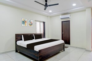 A bedroom with a bed, ceiling fan, air conditioning unit, and artwork on the wall. - Hotel O Ramavarapadu Near PVR Icon (Penumuluru)