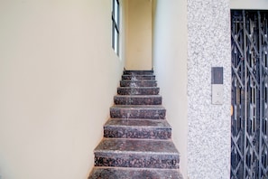 A staircase with a handrail leading to a door with a metal grille. - Hotel O Ramavarapadu Near PVR Icon (Penumuluru)