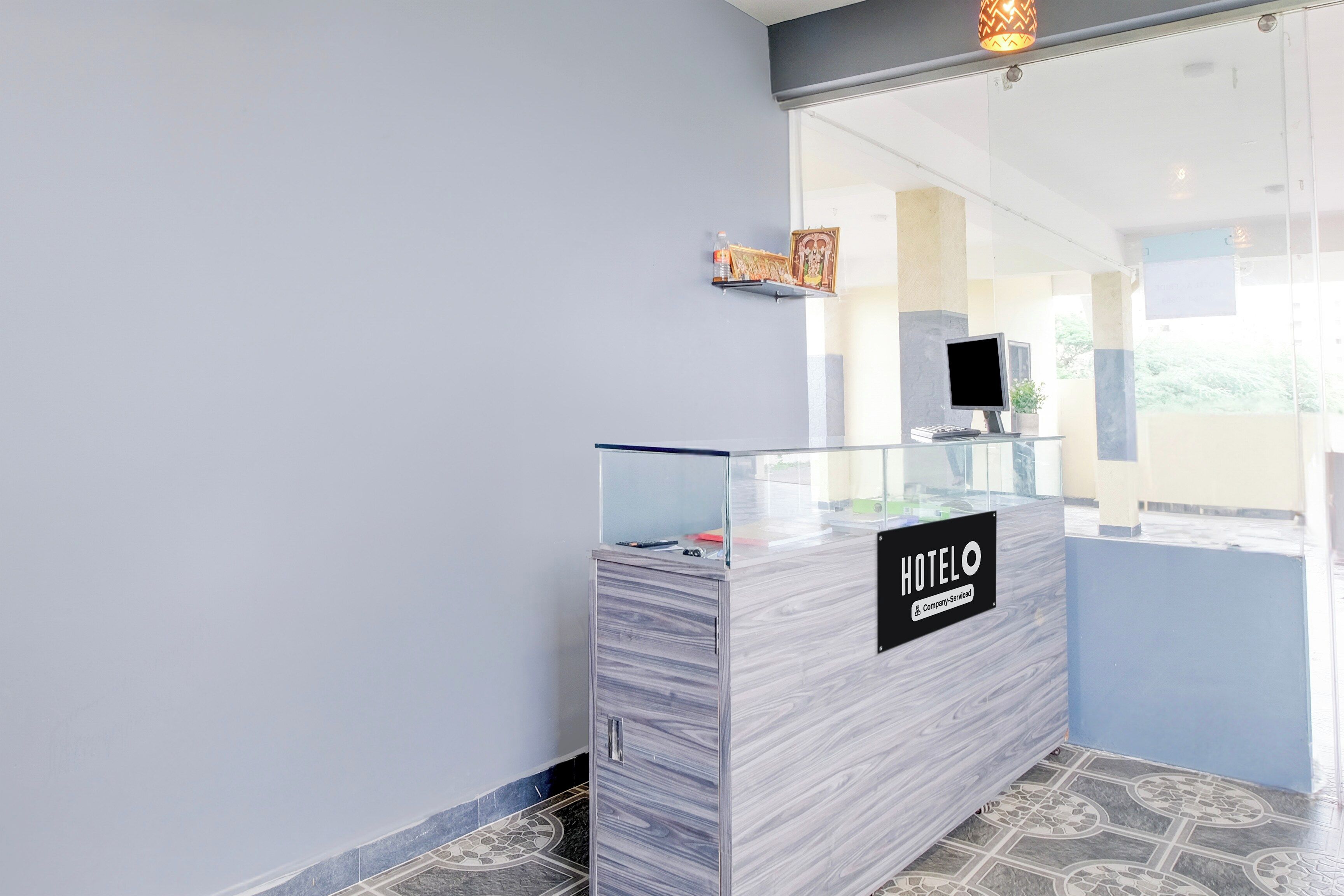 A reception desk with a 'HOTEL' sign, a computer, and a small shelf with items.