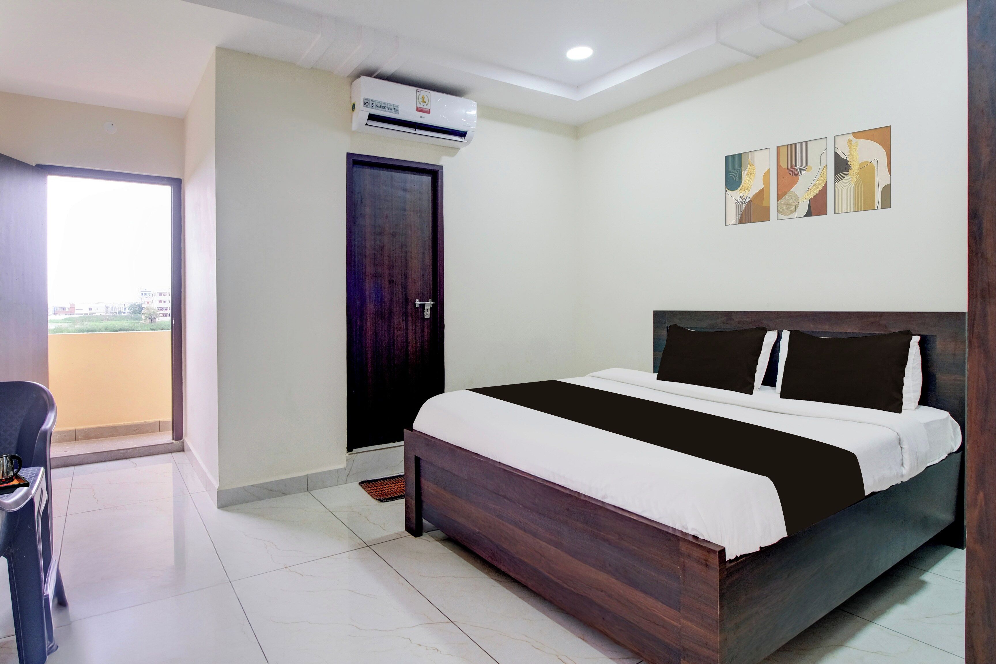 Een hotelkamer met een bed, een deur, een airconditioning, een stoel en uitzicht op het exterieur.