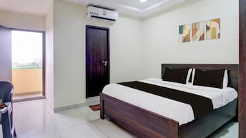 Een hotelkamer met een bed, een deur, een airconditioning, een stoel en uitzicht op het exterieur.