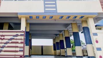 Entrada de um prédio com marquise, colunas e área cercada.