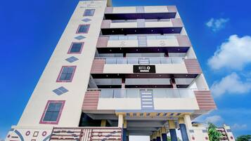 Um hotel com vários andares e design moderno, com uma placa de 'HOTEL' bem visível na fachada.