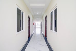 A long, narrow hallway with doors on both sides, leading to rooms. - Hotel O Ramavarapadu Near PVR Icon (Penumuluru)