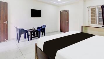 A hotel room with a bed, a desk with chairs, a television, and two wardrobes.