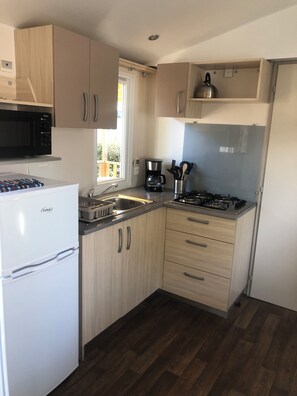 A compact kitchen with a refrigerator, microwave, coffee maker, and stove. - Mobile Home for 2–6 People (Saint-Georges-de-Didonne)