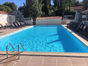Piscina rectangular con solárium empedrado y barandillas metálicas.
