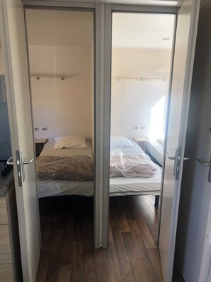 Una habitación con dos camas, suelo de madera y una puerta corredera.