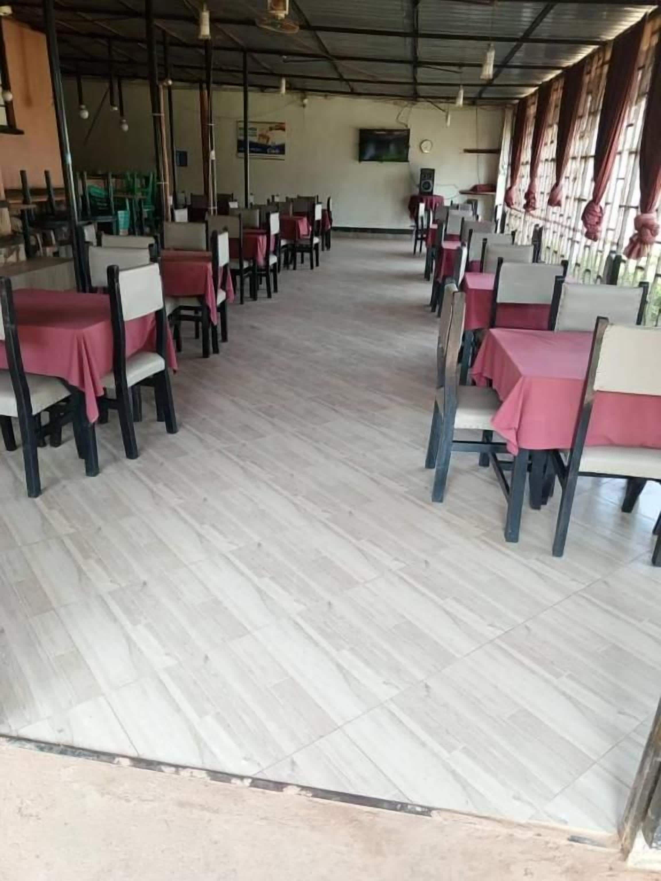 Un restaurante con filas de mesas y sillas, piso de baldosas y techo alto.