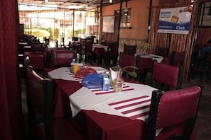 A restaurant with tables set for dining, a banner advertising a club, and a view of the outside.