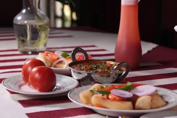 A table with plates of food, a bottle, and a pitcher.