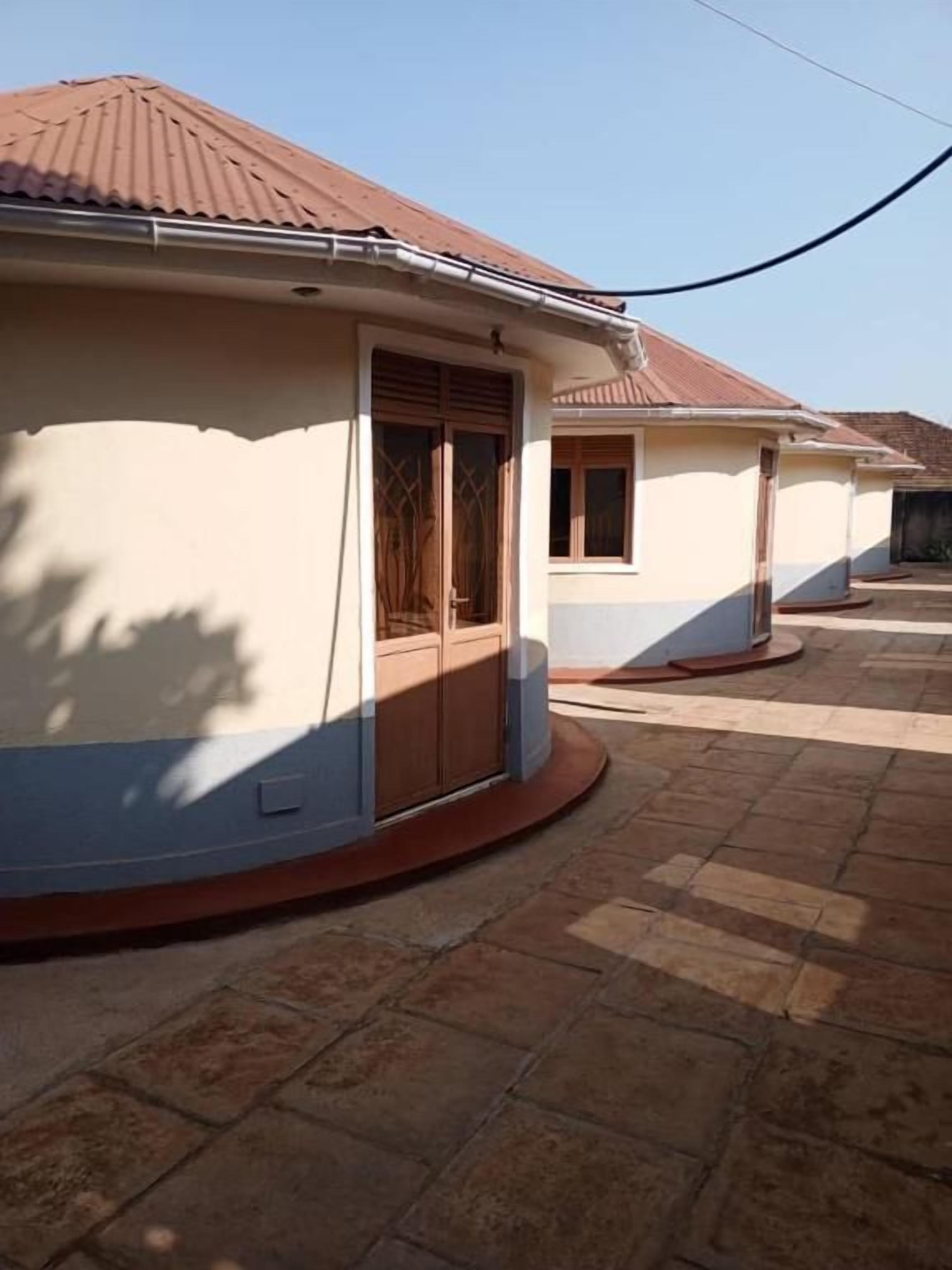 En bostadsbyggnad med en böjd fasad, ett tak täckt med takpannor och en stenlagd innergård.