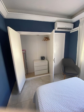 Une chambre à coucher comprenant un lit, une armoire, une chaise et un appareil de climatisation.