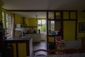 A kitchen with a view to the garden, a dining area with a table and chairs, and a window with curtains.